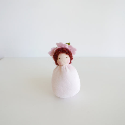 Small doll with a pink flower on a white background