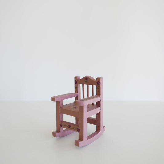 Handcrafted dolls house furniture: small primrose-colored rocking chair with classic spindle back, shown against white