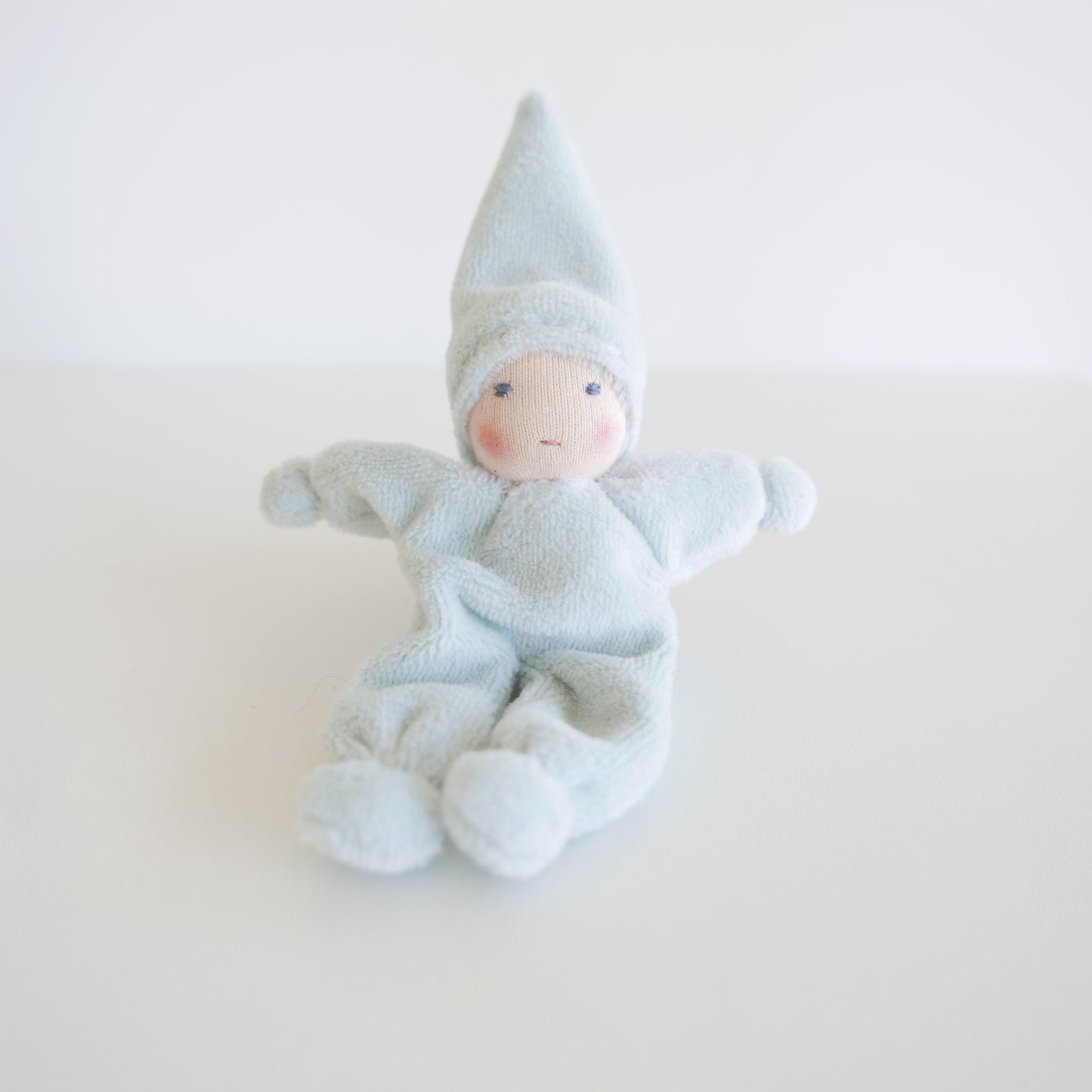 Textile baby doll with a blue outfit on a white background