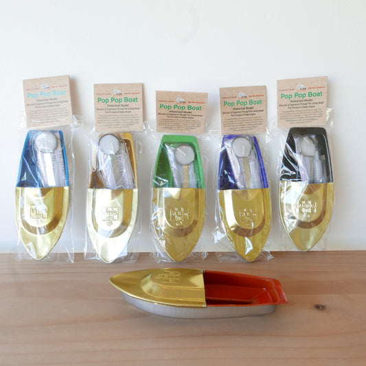 Set of Pop Pop Boat toys in packaging on a wooden surface with a white background