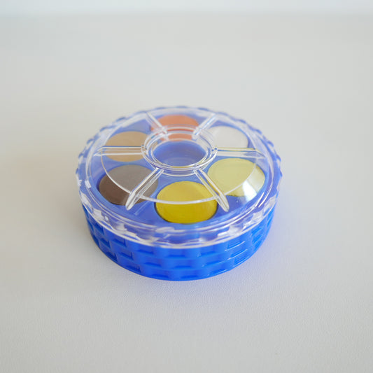 Round container with colorful circular pads on a white background