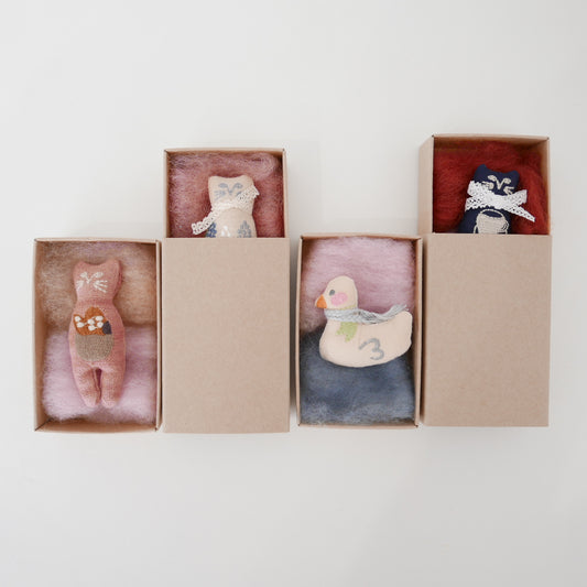 Set of baby stuffed toys with animal designs in cardboard boxes on a white background