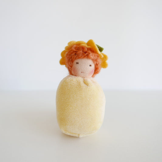 Small doll with orange hair and a yellow dress on a white background
