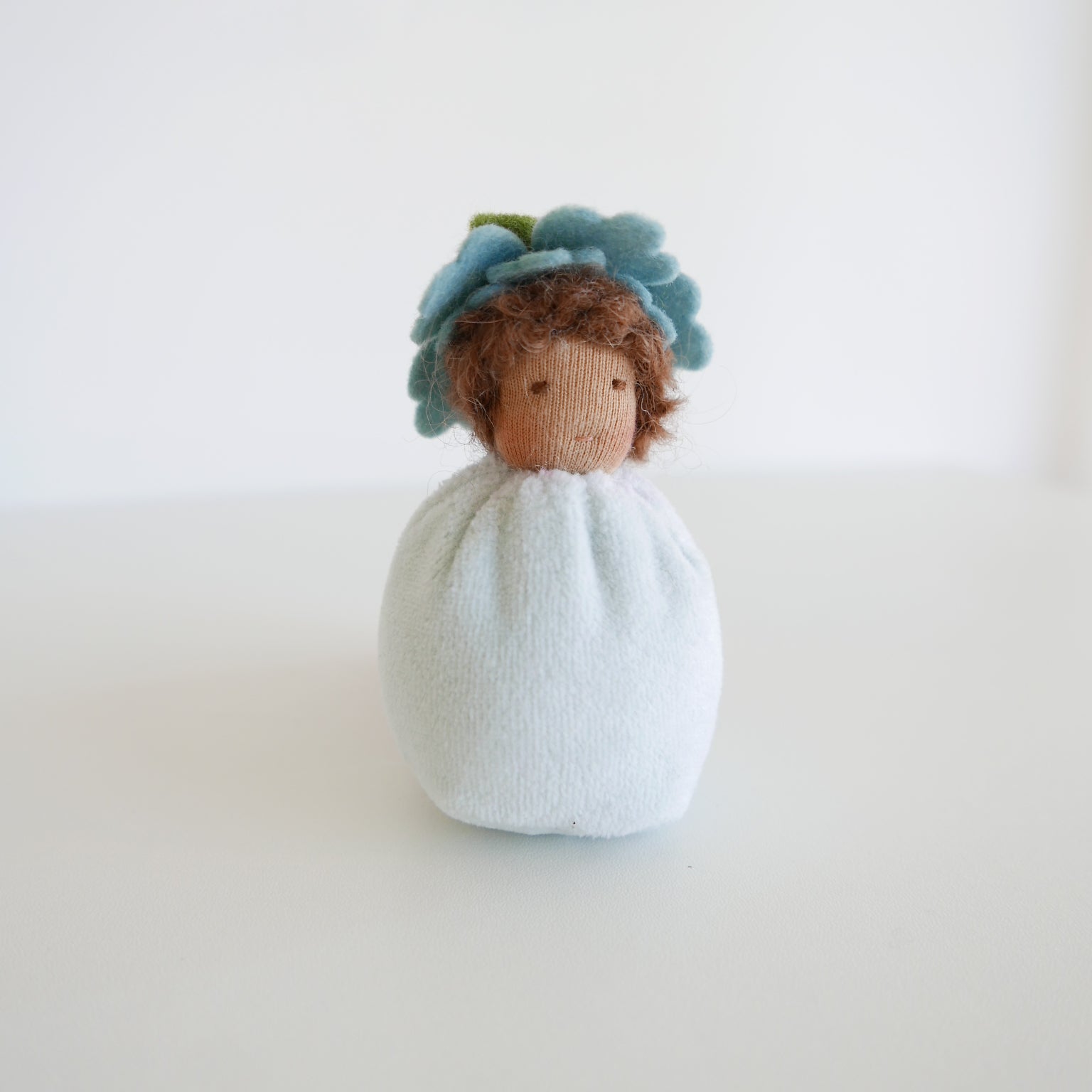 Soft cloth doll with violet dress, flower crown and gentle features, designed for imaginative play, displayed against white

