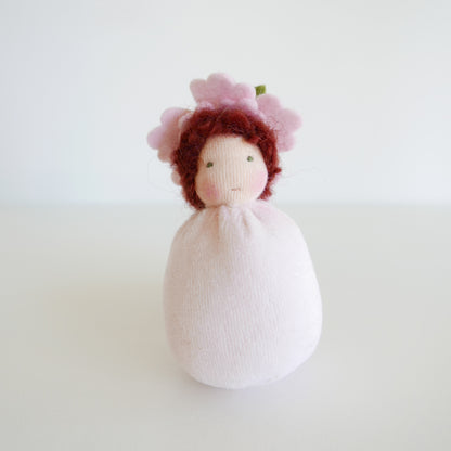 Knitted doll with red hair and a white dress on a light background