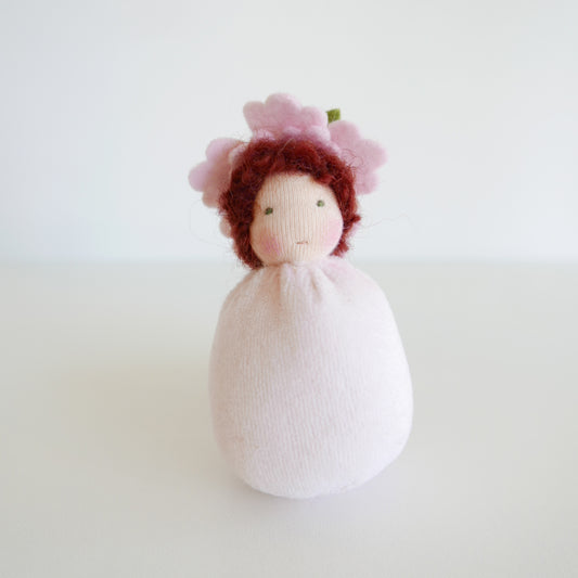 Knitted doll with red hair and a white dress on a light background