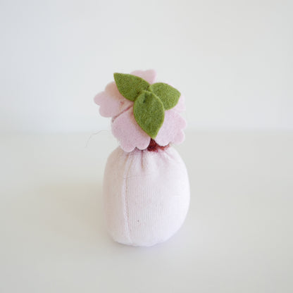 Small pink bath bomb with green leaves on a light gray background