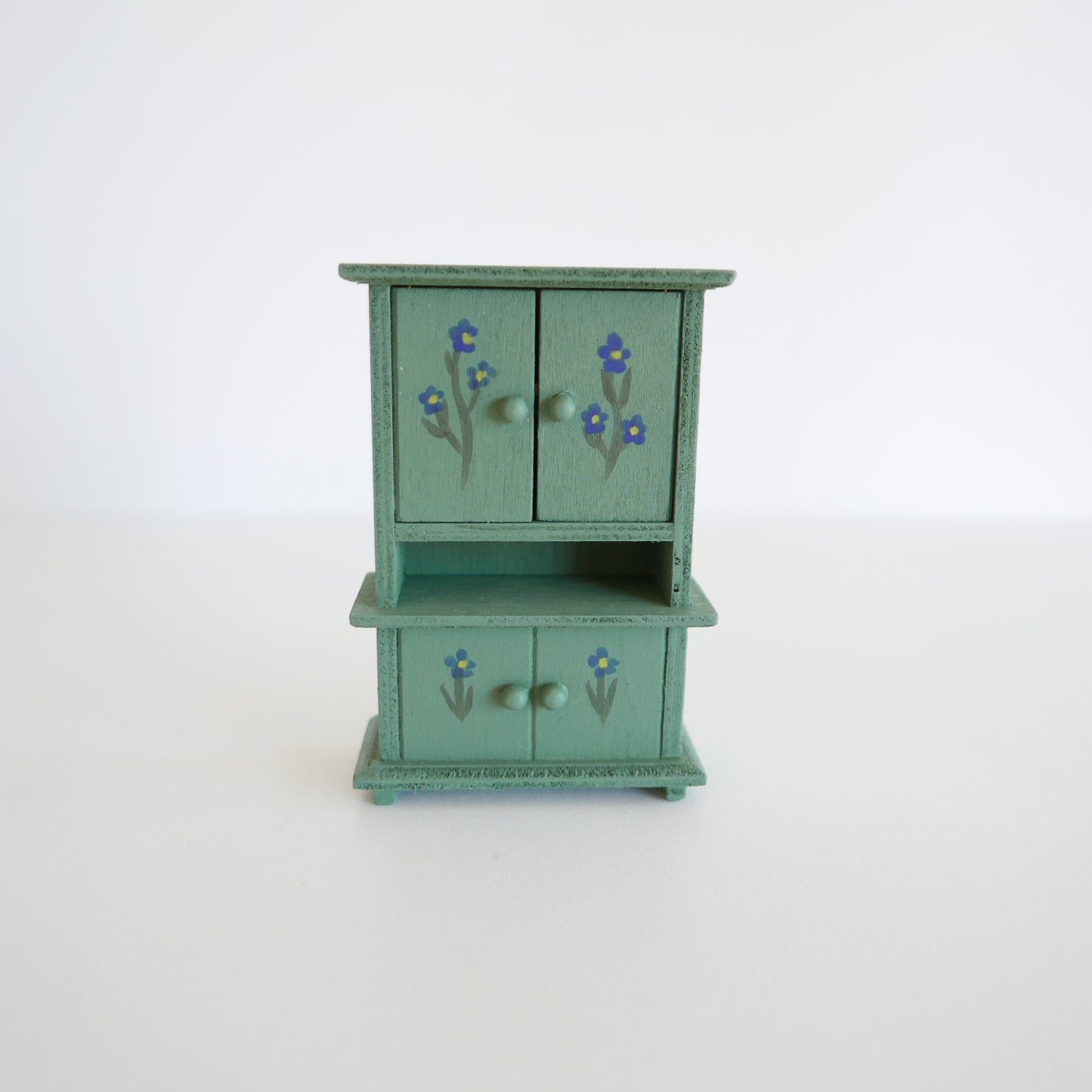 Small green wooden cabinet with floral designs on a white background