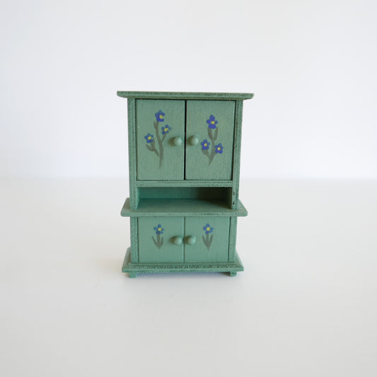 Small green wooden cabinet with floral designs on a white background
