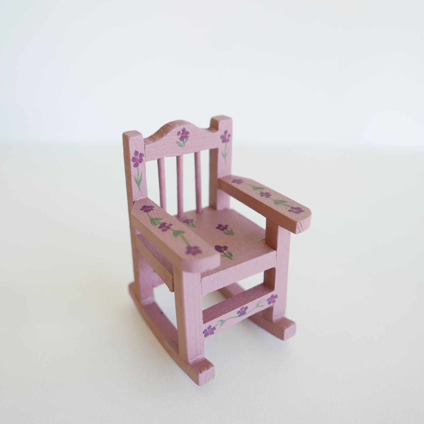 Miniature wooden rocking chair painted in soft primrose yellow, designed for a dolls’ house, photographed on a white background