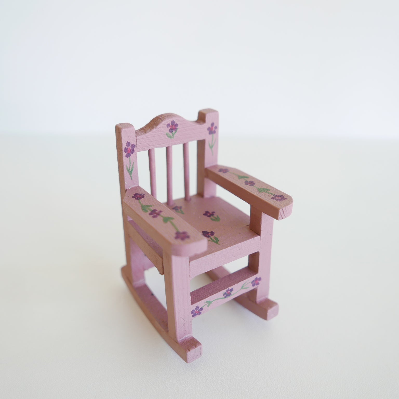 Miniature wooden rocking chair painted in soft primrose yellow, designed for a dolls’ house, photographed on a white background