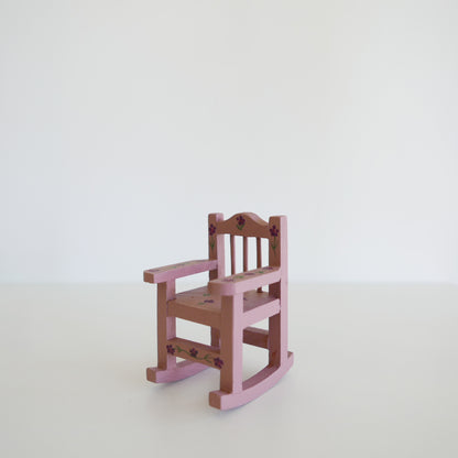 Handcrafted dolls house furniture: small primrose-colored rocking chair with classic spindle back, shown against white