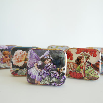 Vintage-style tin boxes with fairy designs on a white background