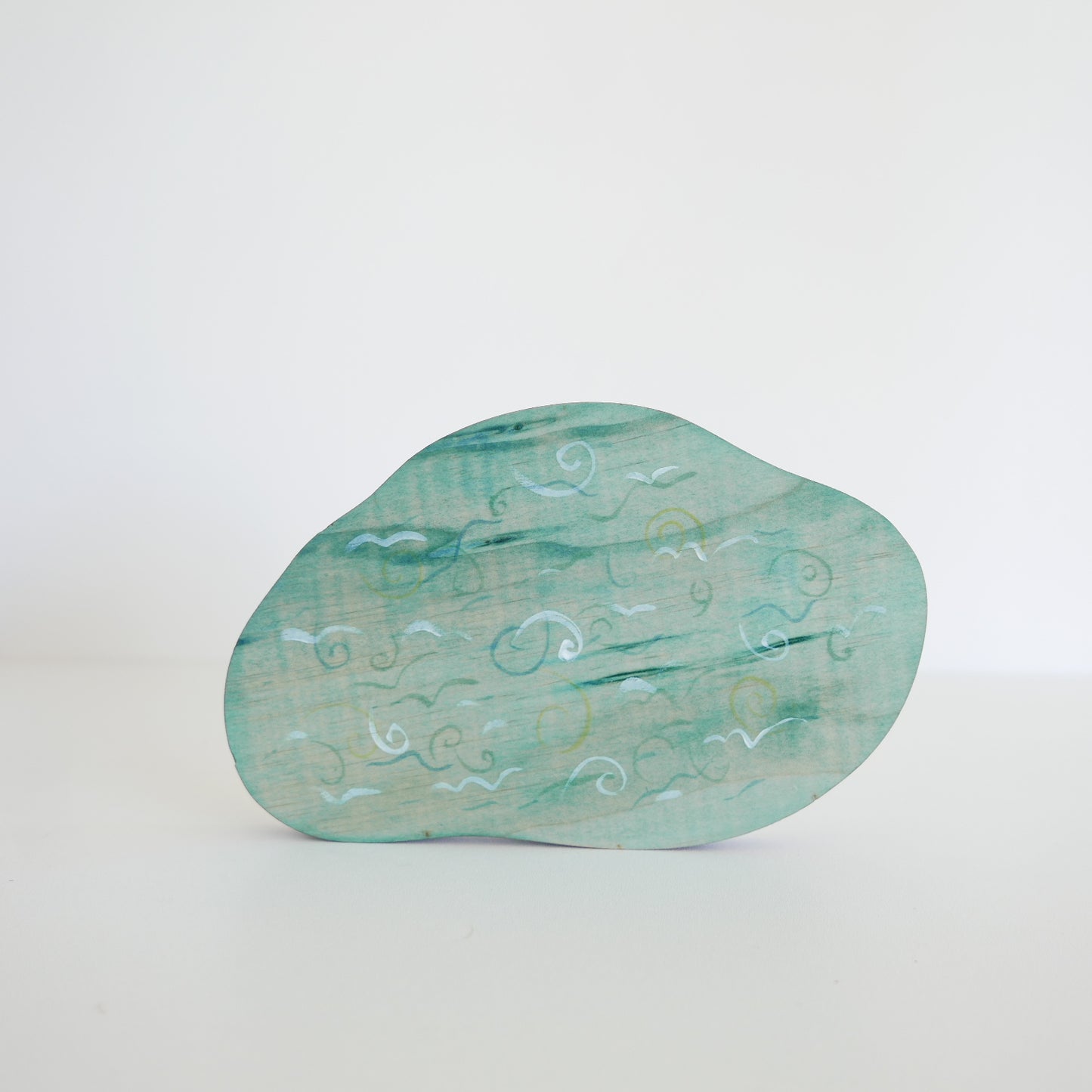 Teal glass object with engraved patterns on a white background