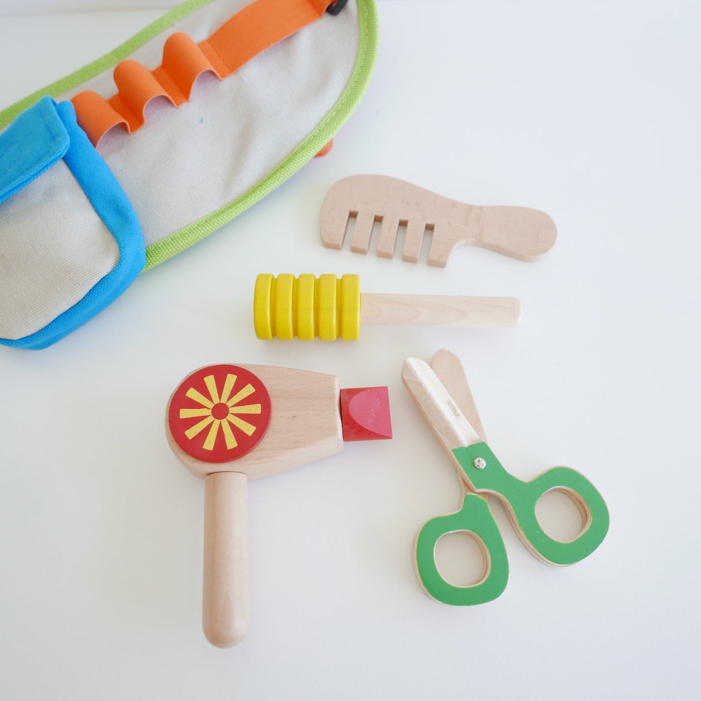 Set of colorful children's play tools including a hammer, scissors, and other items for hairdressing pretend play