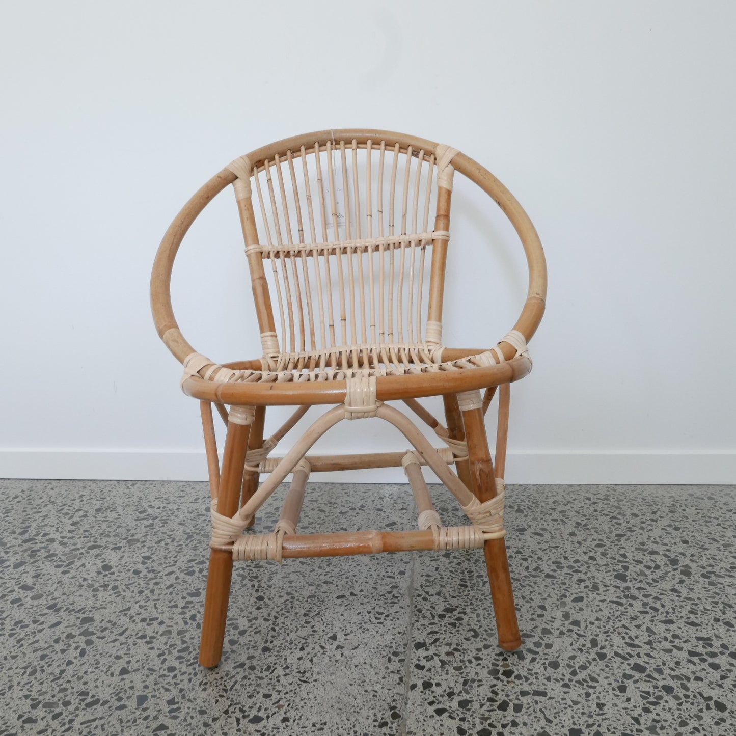 Wicker chair with round backrest on a concrete floor against a white wall