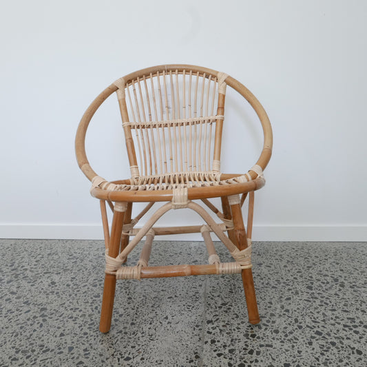 Wicker chair with round backrest on a concrete floor against a white wall