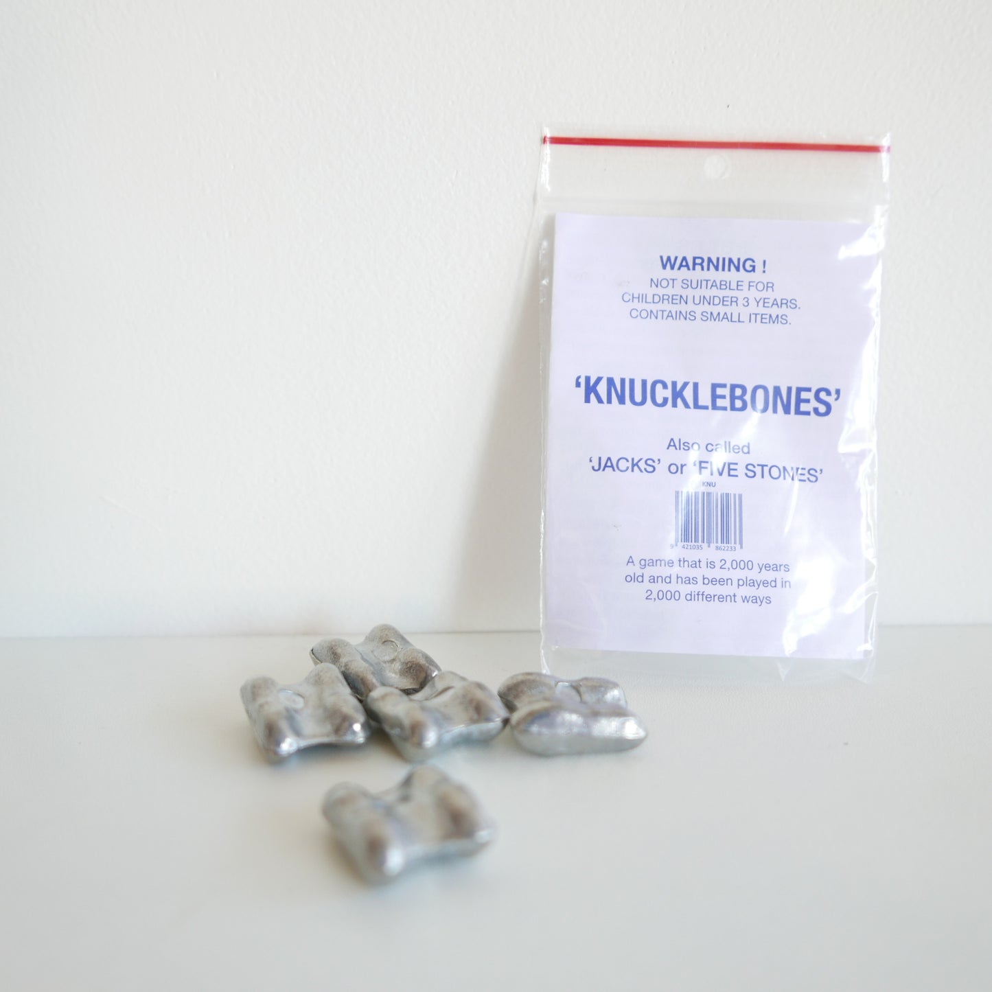 Bag of 'Knucklebones' with warning label on a white background