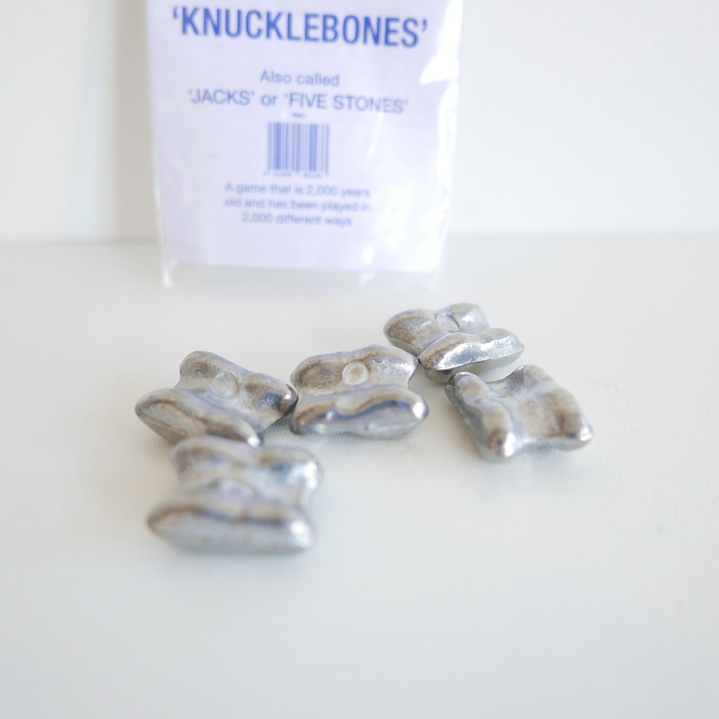 Silver knucklebones with packaging labeled 'Knucklebones' on a white background