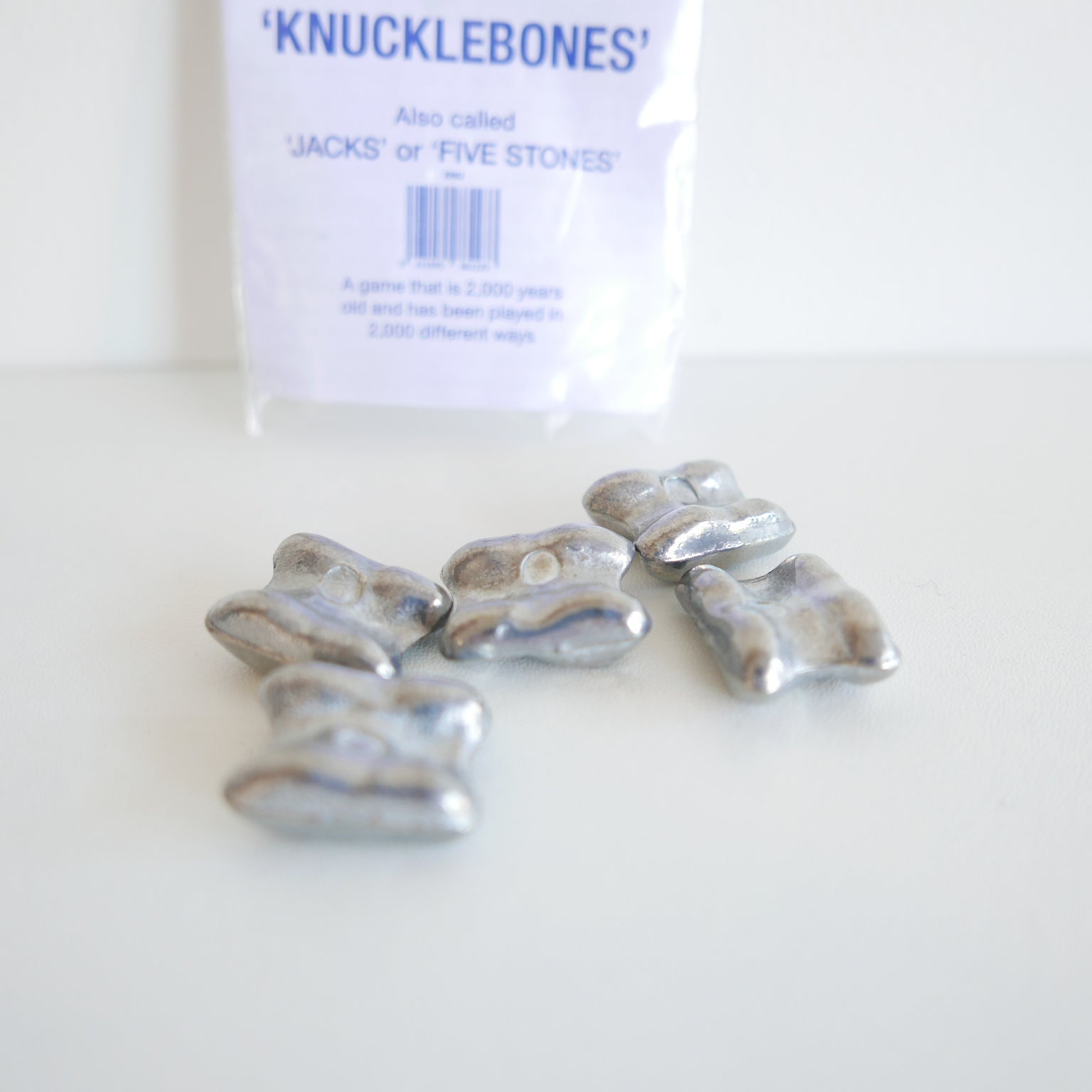 Silver knucklebones with packaging labeled 'Knucklebones' on a white background