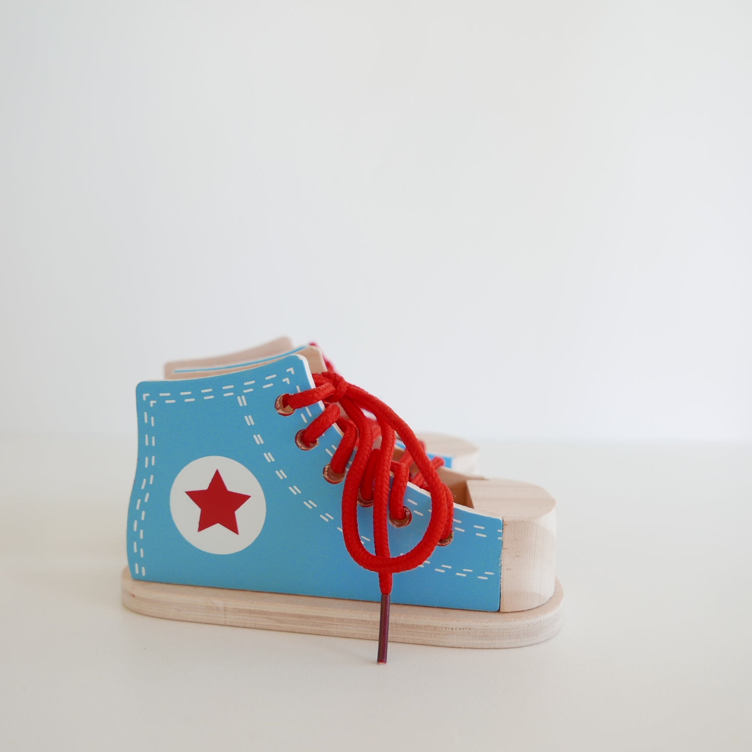 Toy shoe with red laces and a red star on a light gray background