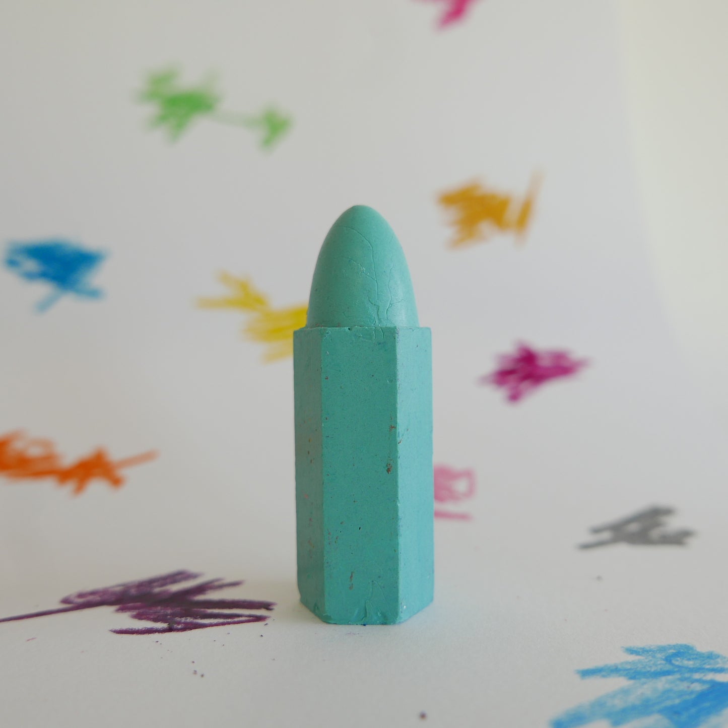 Green crayon on a white background with colorful crayon strokes