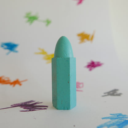 Green crayon on a white background with colorful crayon strokes