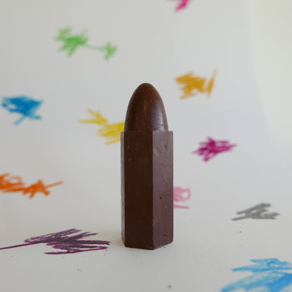 Chocolate brown crayon on a white background with colorful crayon marks