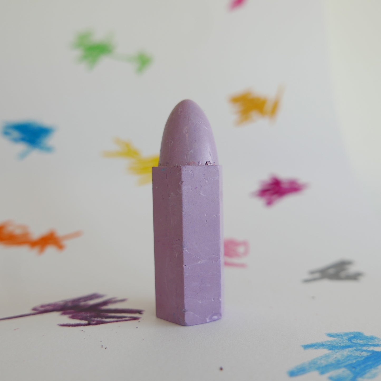 Purple crayon on a white background with colorful crayon marks