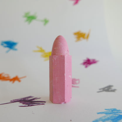 Pink crayon on a white background with colorful scribbles