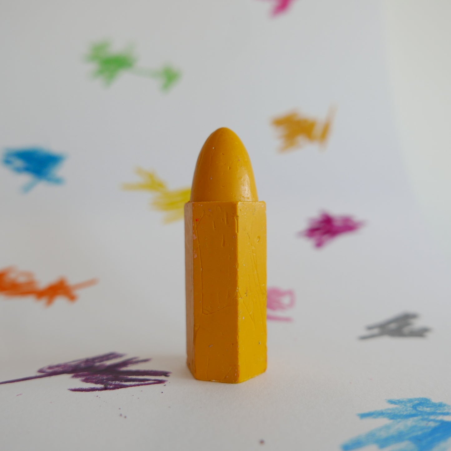 Yellow crayon on a white background with colorful scribbles