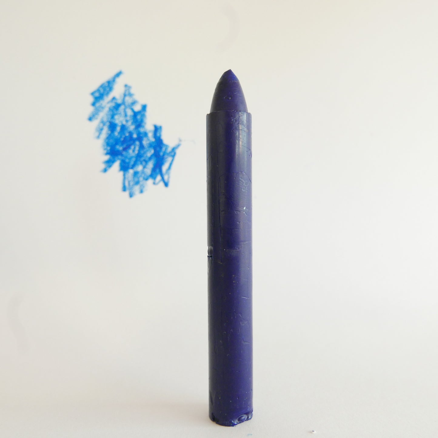 Blue crayon with a small blue scribble on a white background