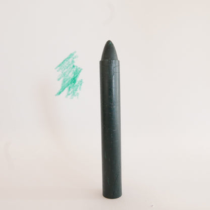 Black crayon with a small green scribble on a white background