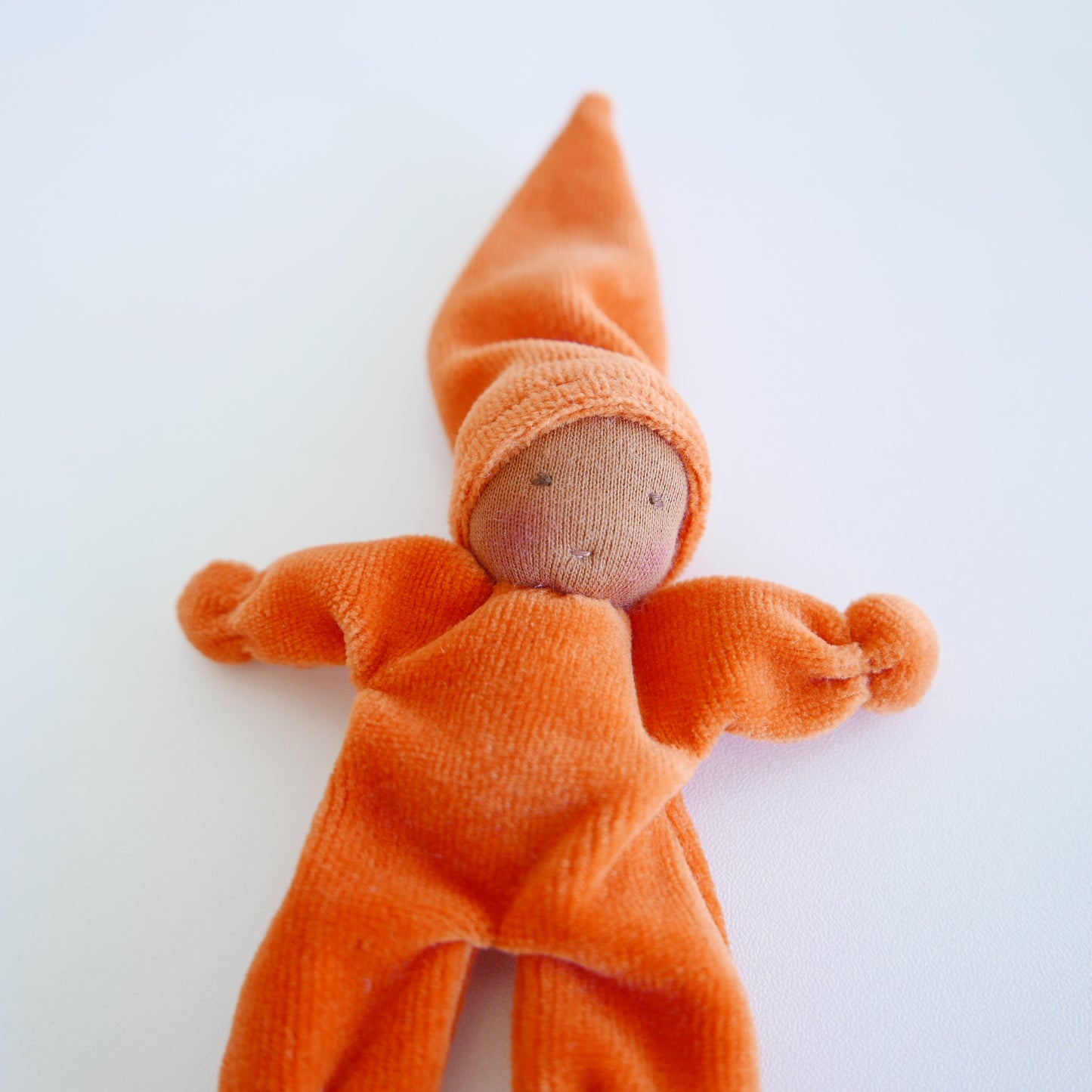 Small doll with an orange outfit on a white background