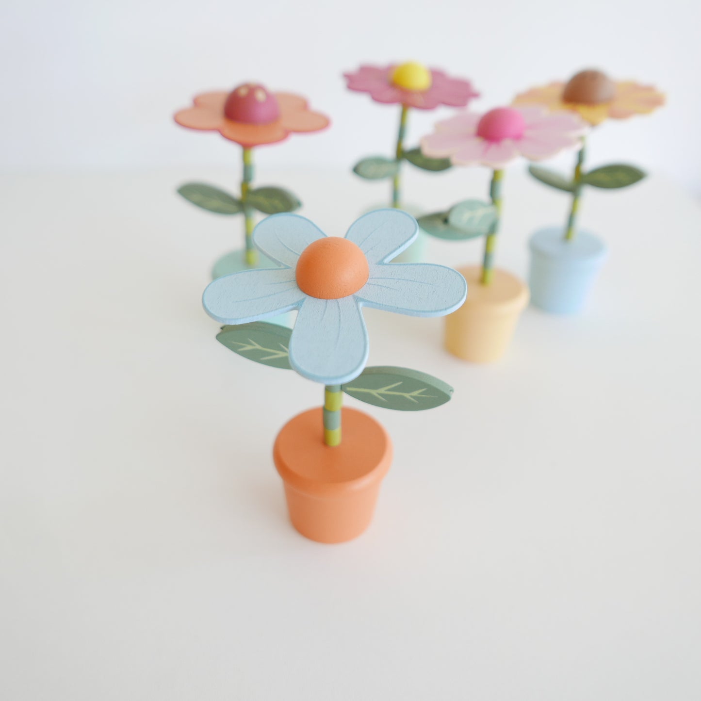 wooden Colorful flower-shaped objects with green stems on a white background