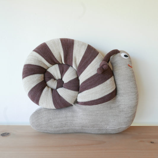 Knitted snail toy with striped shell on a wooden surface