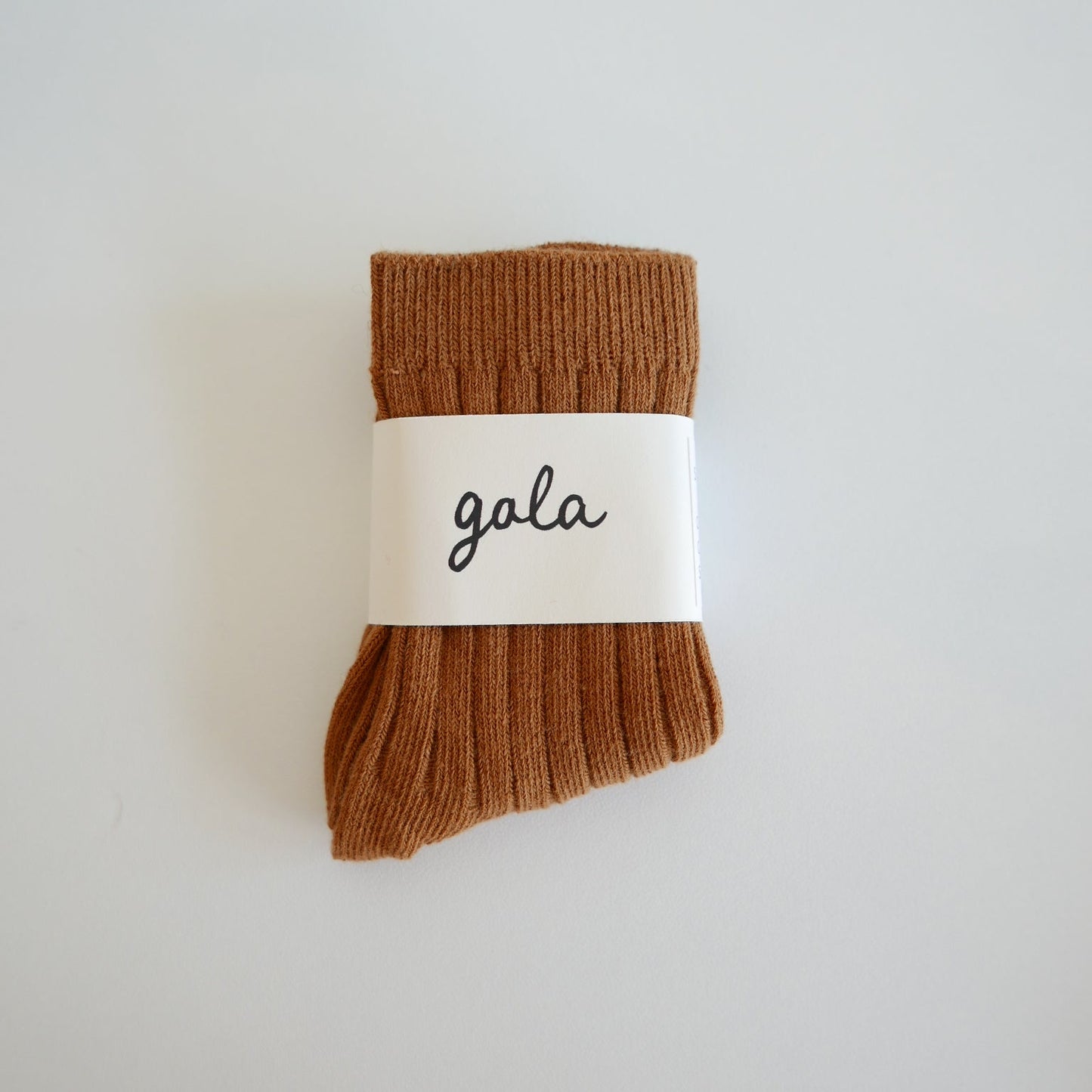 Pair of brown socks with a 'gala' label on a light gray background