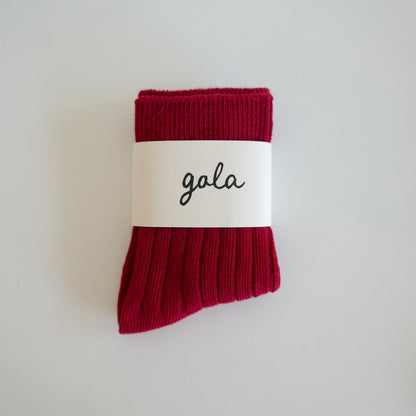 Red sock with a white label displaying the word 'gala' on a light gray background