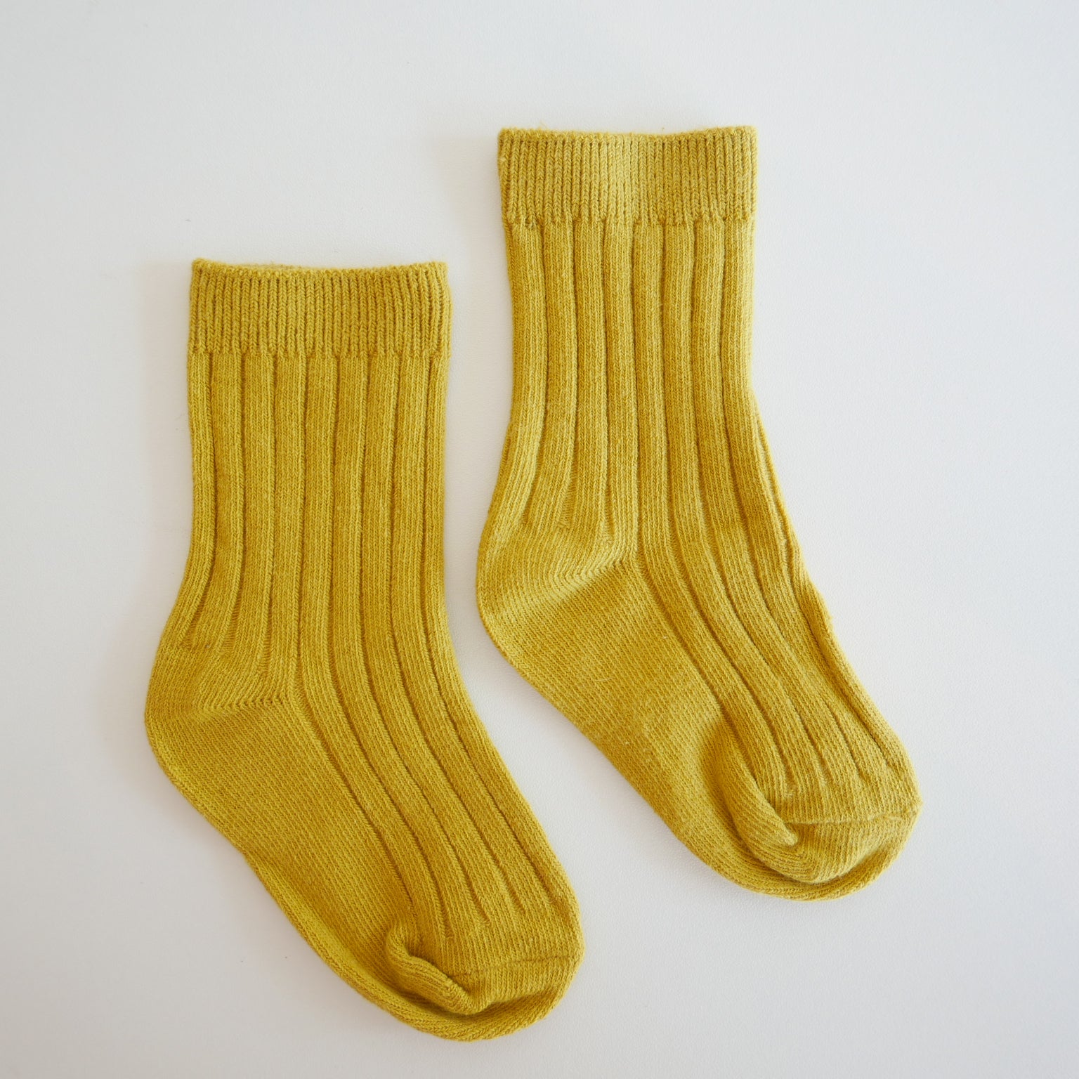 Pair of mustard yellow socks on a light gray background