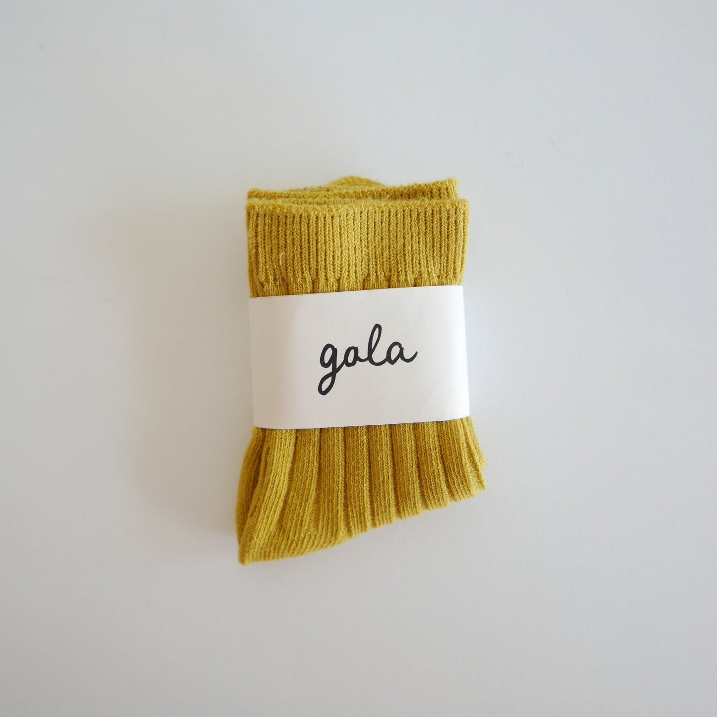 Mustard yellow socks with a white label on a light gray background