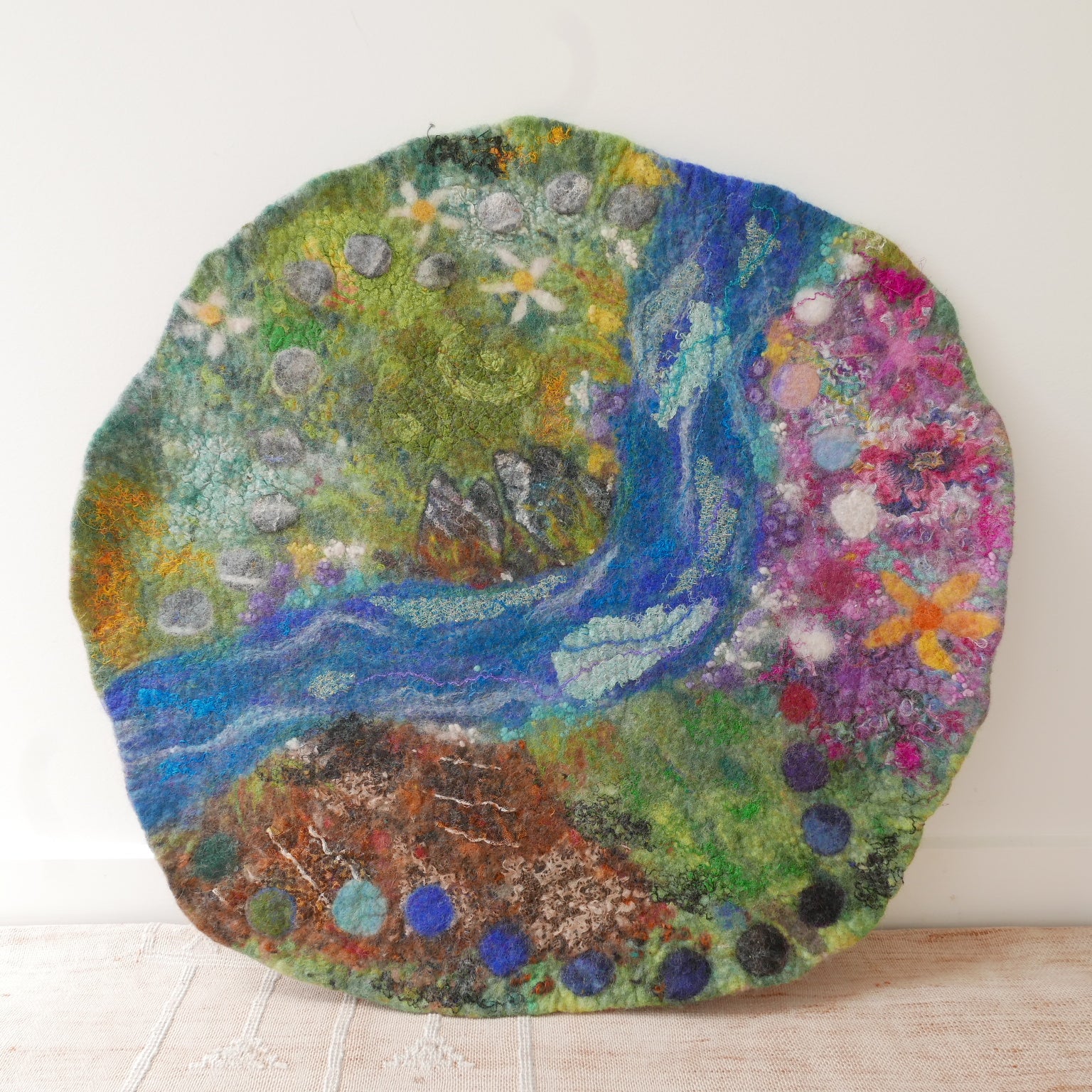 Round colorful rug with nature-themed design on a wooden floor.