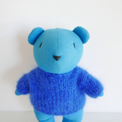 Blue teddy bear with a blue knitted sweater on a white background