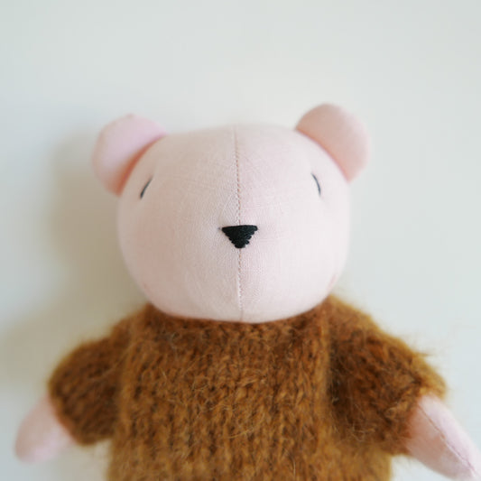Small plush toy with a pink face and brown body on a white background