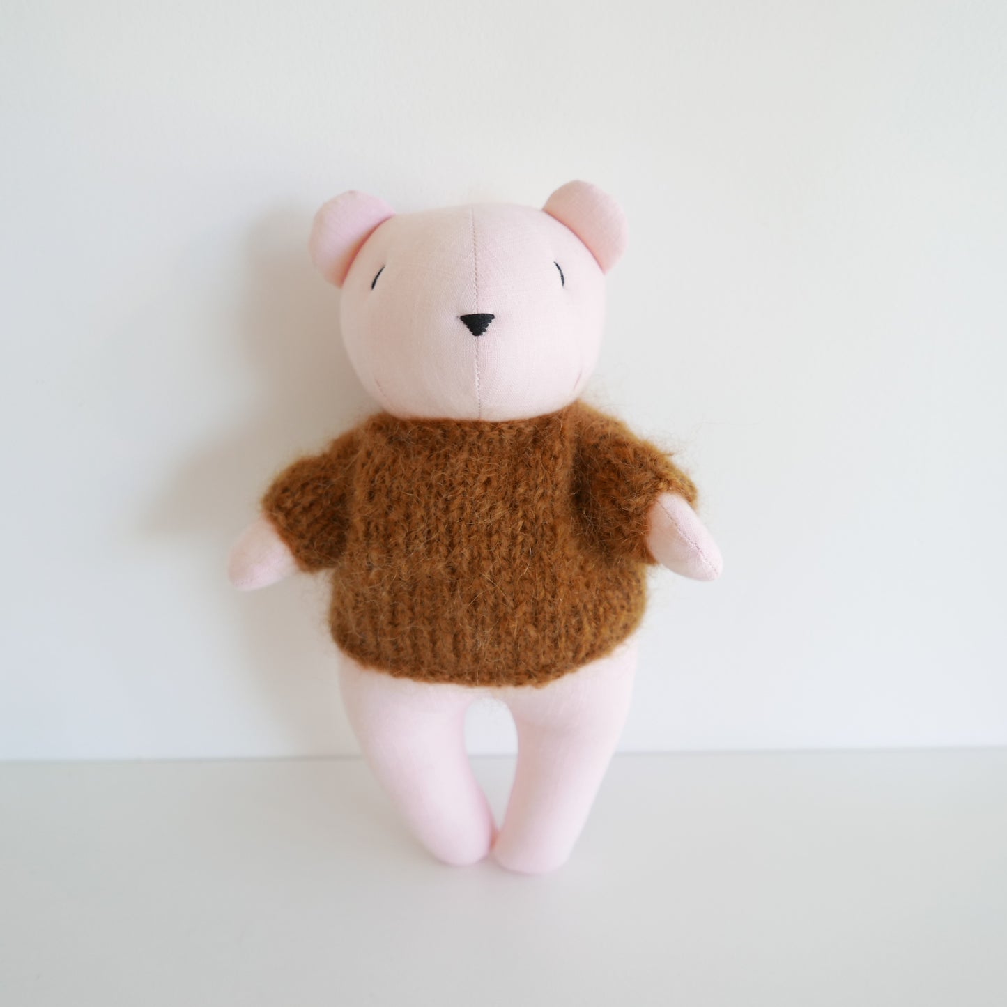 Cute plush bear with a pink face, copper brown body, and hand-knitted mohair jumper, photographed on a white background