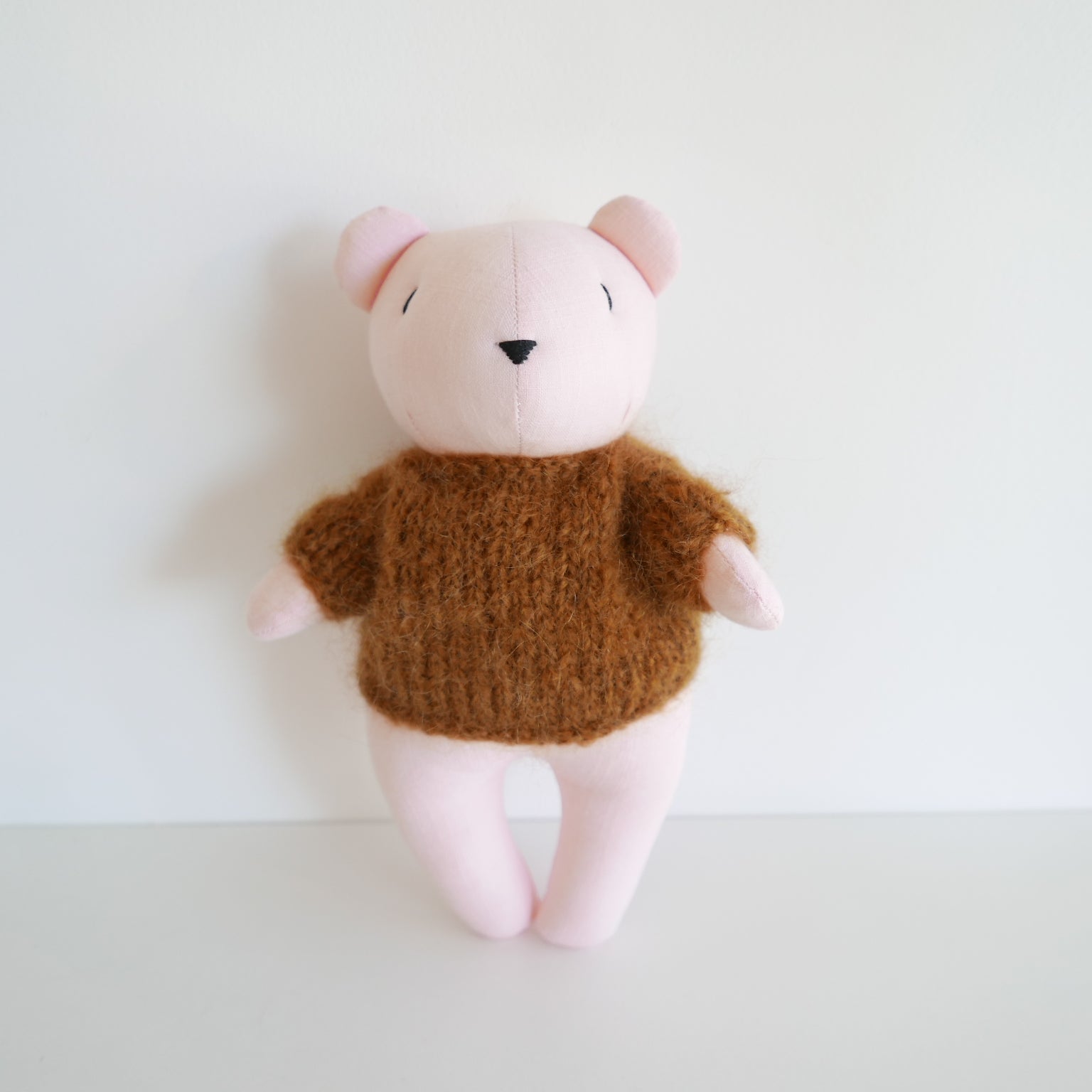 Cute plush bear with a pink face, copper brown body, and hand-knitted mohair jumper, photographed on a white background