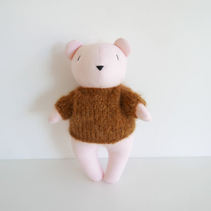 Cute plush bear with a pink face, copper brown body, and hand-knitted mohair jumper, photographed on a white background