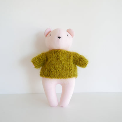 Small plush toy with a green knitted sweater on a white background