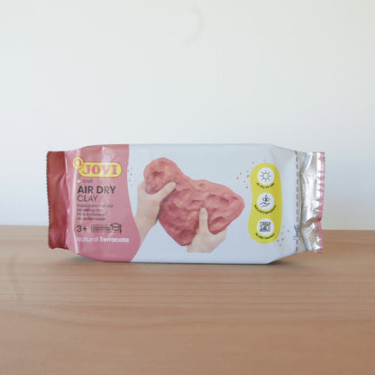 Package of air dry clay with pink material on a wooden surface