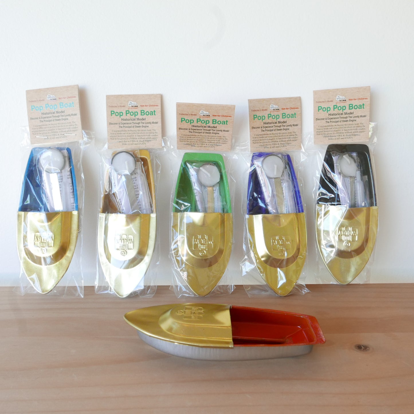 Set of Pop Pop Boat toys in packaging on a wooden surface with a white background