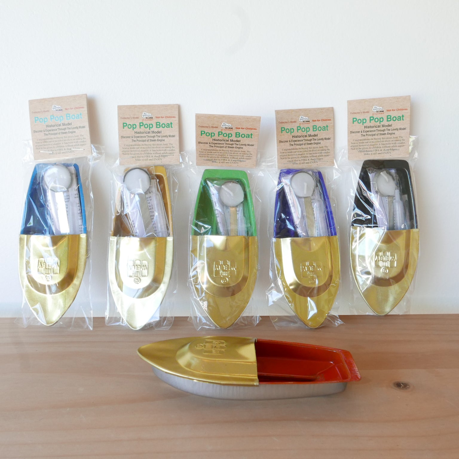 Set of Pop Pop Boat toys in packaging on a wooden surface with a white background